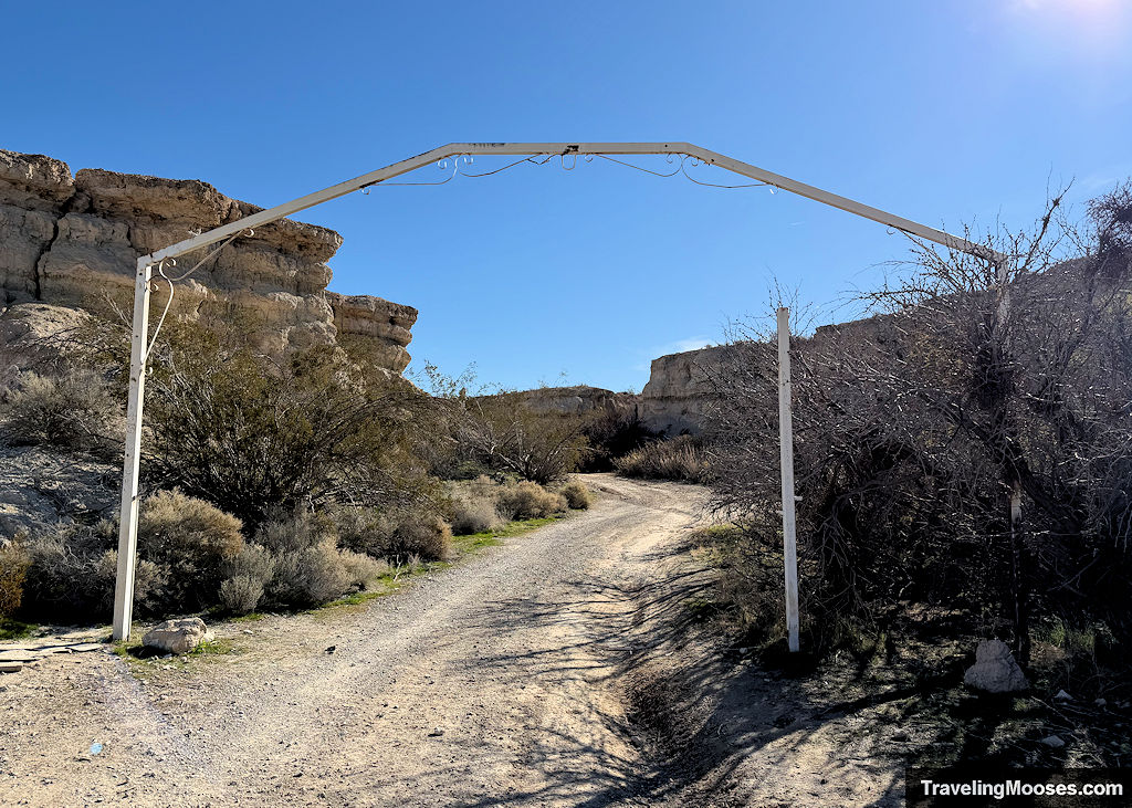 A decayed thin white arch leading into a canyon area over a gravel road