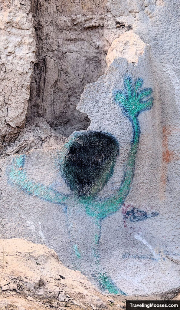 A boy that painted green on a cliff side crawling up with its hand stretched out