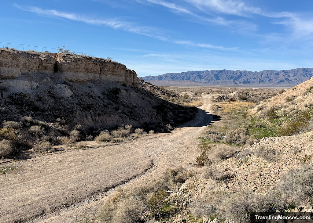 A long gravel road wandering through the desert towards mountains in the distance