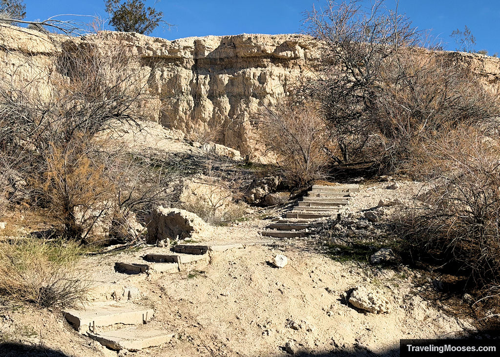 Decayed wooden steps leading up a hill side within a canyon on a sunny day