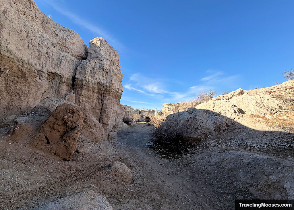 A gravel road leading through a canyon towards a Christ of the Andes Statue
