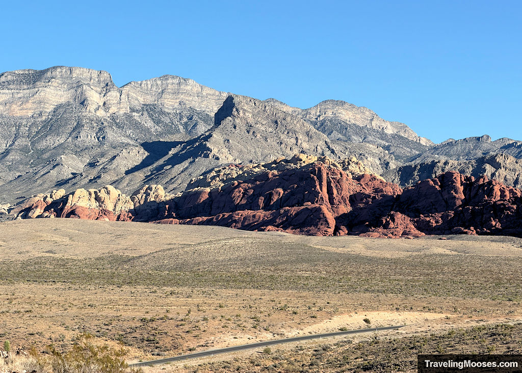 Red and white sandstone rock formations with rocky peaks in the background