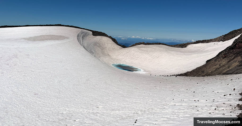 Teardrop lake within a snow field on South Sister Summit