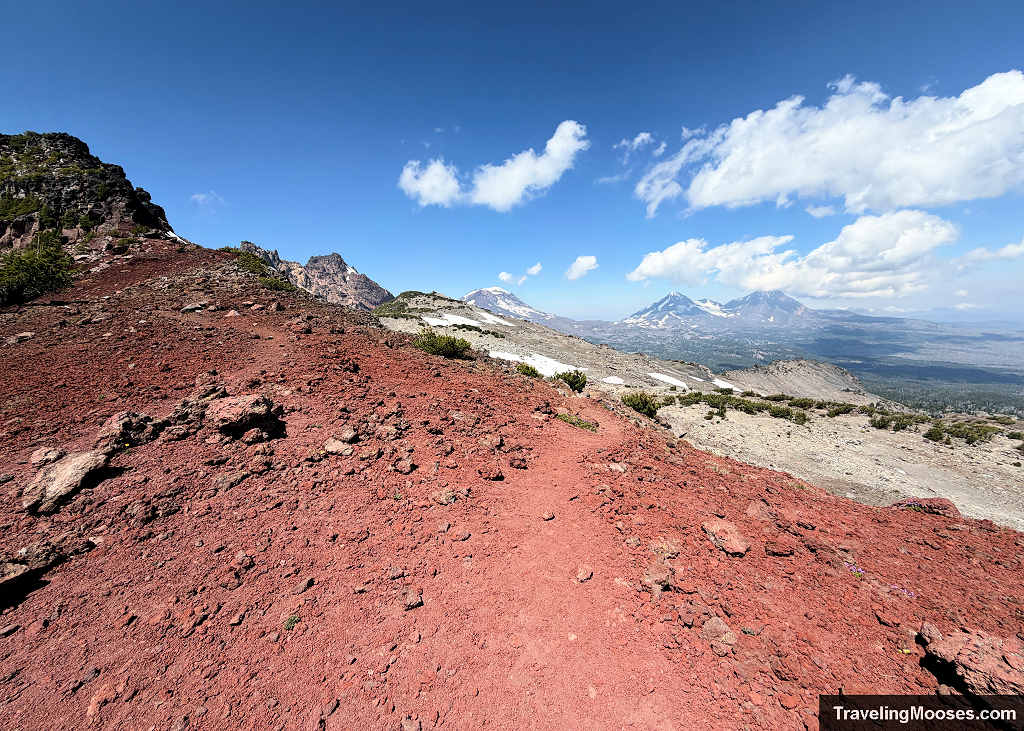 Fork in the red volcanic cinder trail near Broken Hand with Broken Top and the Three Sisters on the horizon