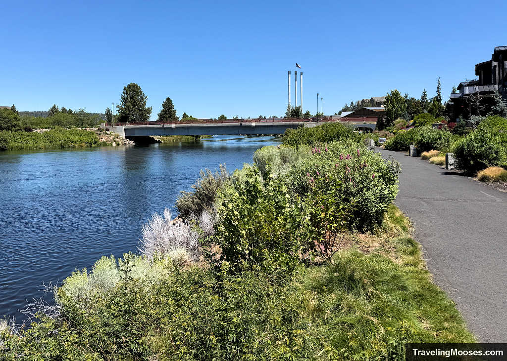 Riverwalk trail on the Deschutes river with a bridge and smokestacks in the distance