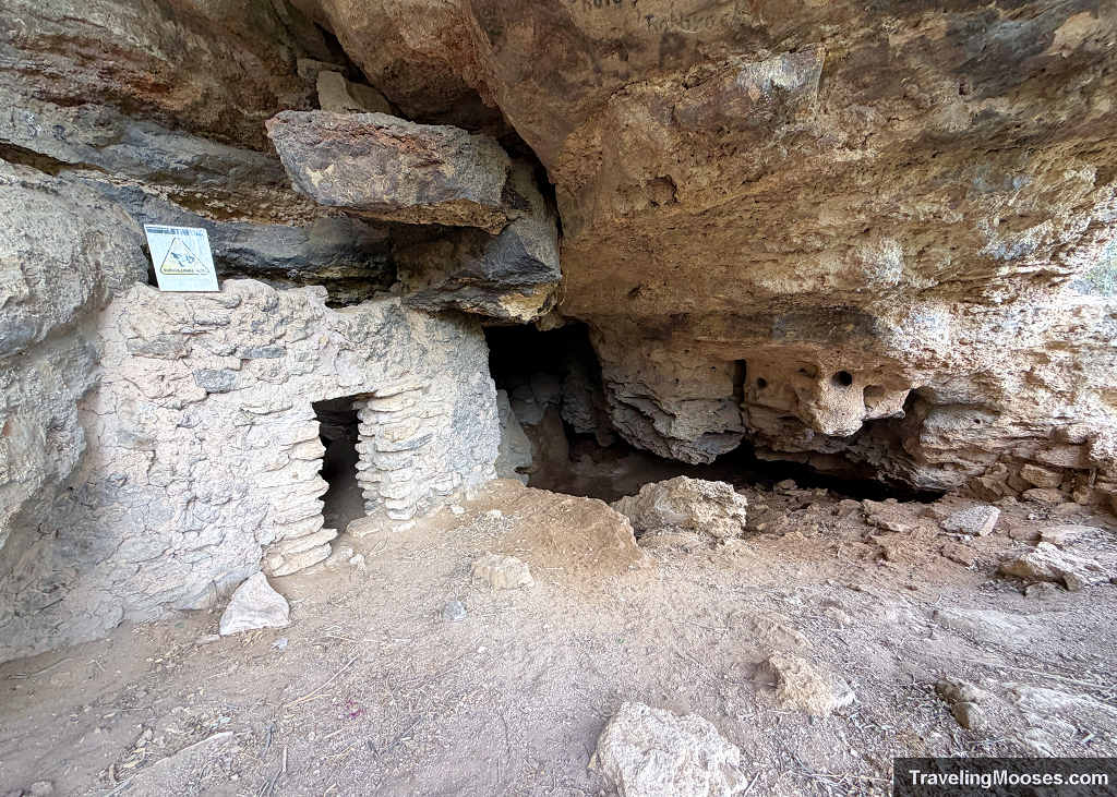 Ancient stone-and-mortar masonry wall with a narrow doorway built directly inside a limestone cave shelter at the bottom of Montezuma Well.