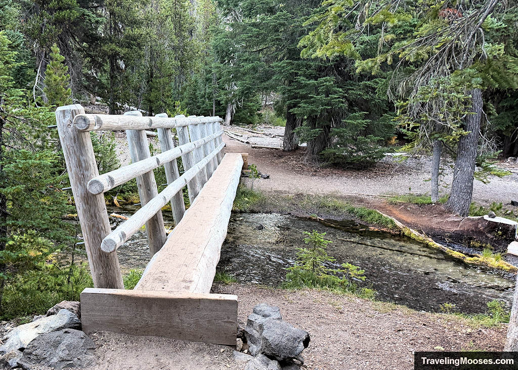Wood bridge with one railing traversing a light mountain stream