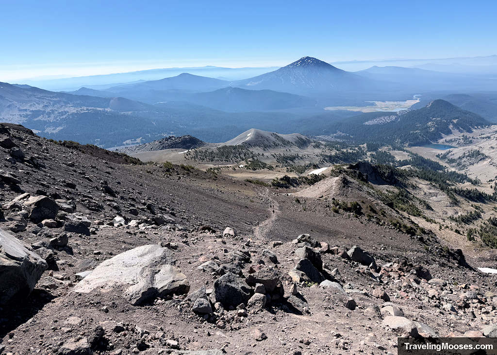 Steep mountain trail with large mountains in the distance on a smoky day
