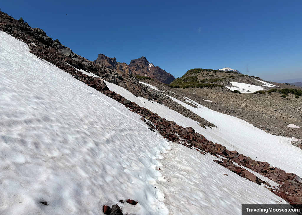 Faint footprints crossing a steep, angled snowfield on the unmaintained trail leading past Broken Hand