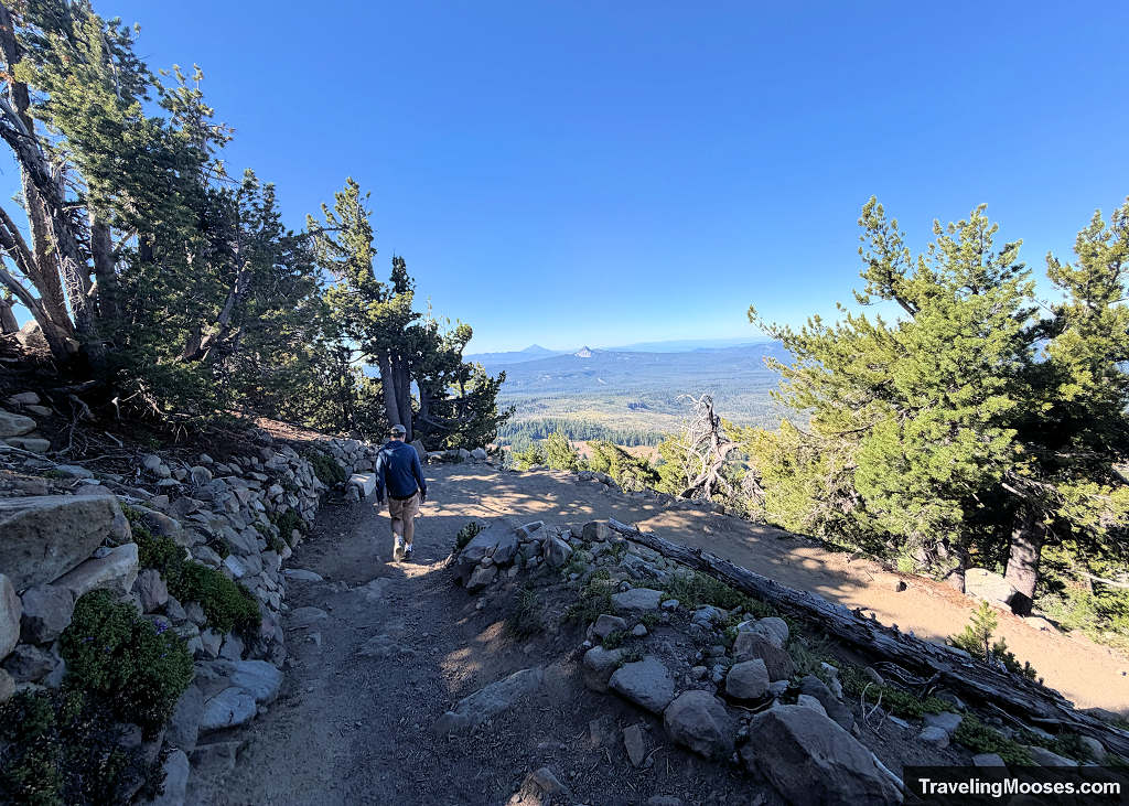 Man walking down switchbacks on a shaded mountain trail