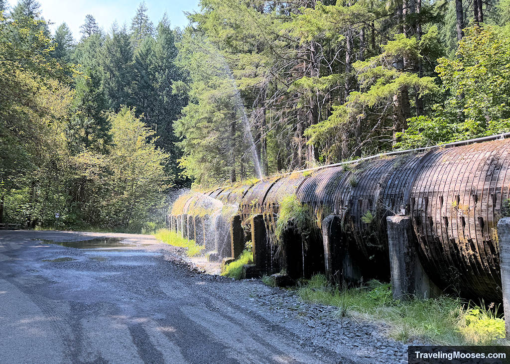 A large wooden pipe with metal slats and water gushing out