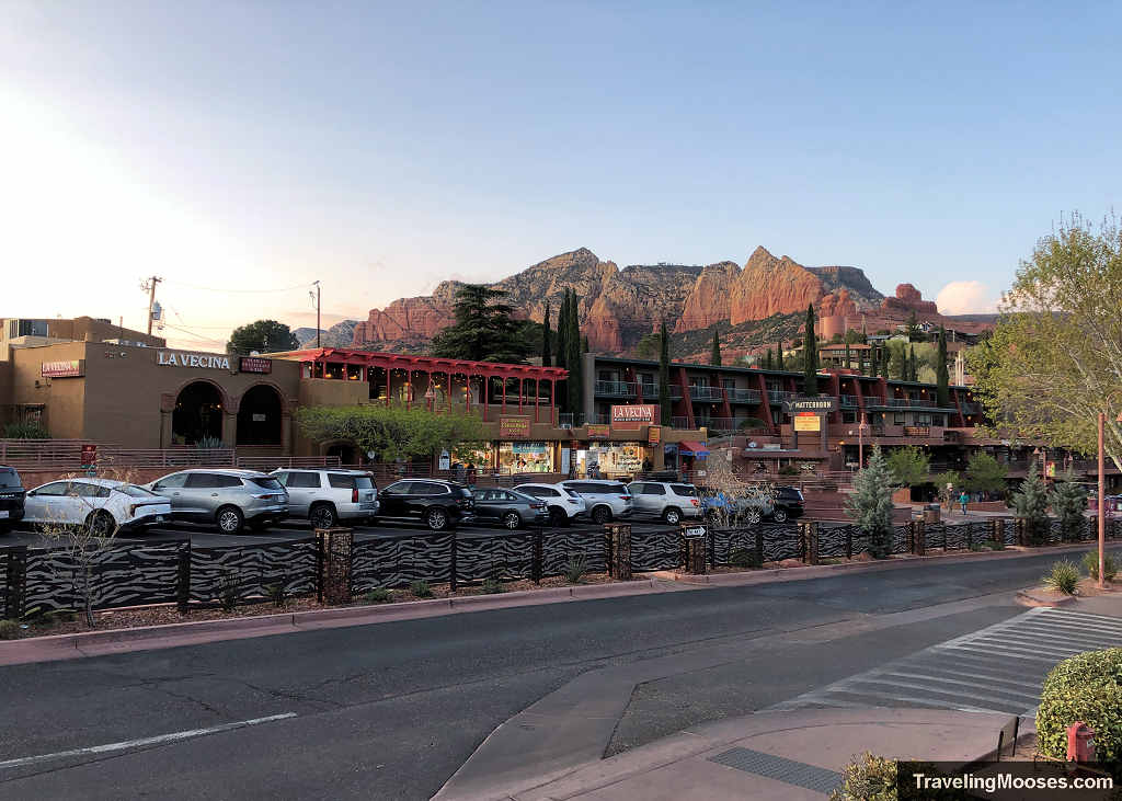 Commercial street view of Uptown Sedona shops and hotels along Highway 89A with red rock mountains in the background.
