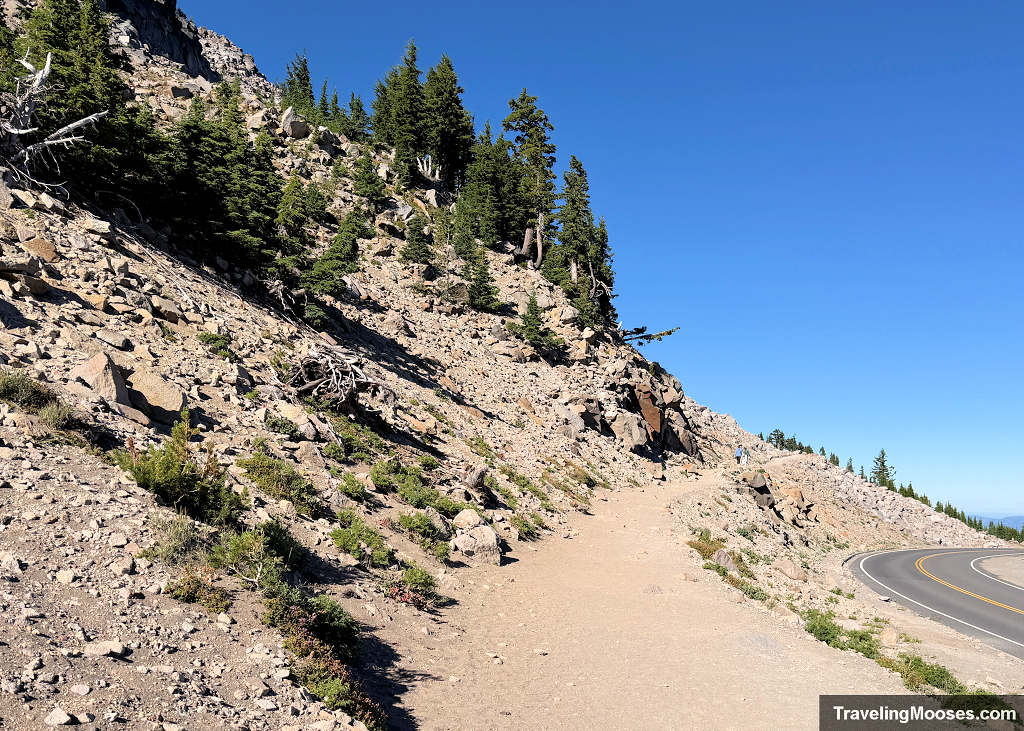 Wide dirt trail running next to a rockfall