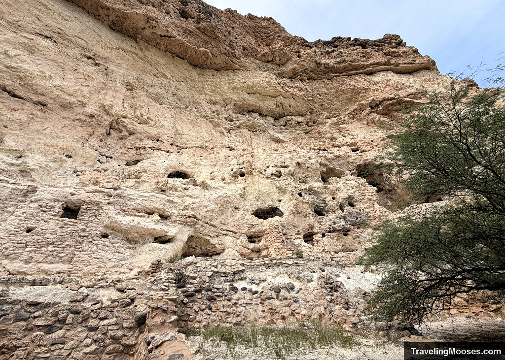 Wide view of the Castle A ruin site showing stacked stone foundation walls and beam socket holes carved into the white limestone cliff face