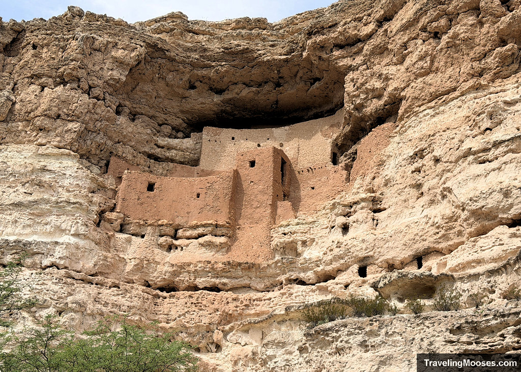 Close-up telephoto view of the five-story ancient Sinagua cliff dwelling built into a recessed white limestone cliff alcove