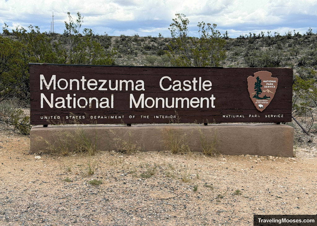 Brown wooden National Park Service entrance sign for Montezuma Castle National Monument set on a concrete base
