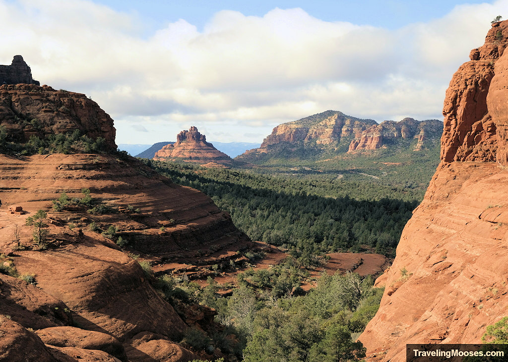 Vast view through a red rock sandstone canyon looking out toward Bell Rock in the distance