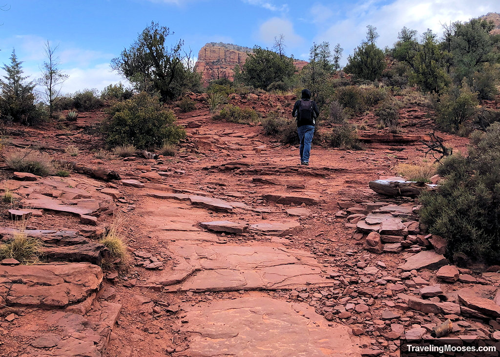 Hiker climbing natural red sandstone steps on a rocky desert trail