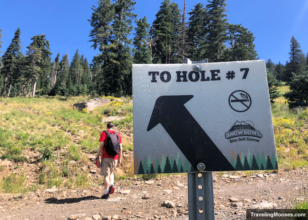 An arrow point to hole # 7 seven with a man walking in the distance towards the hole