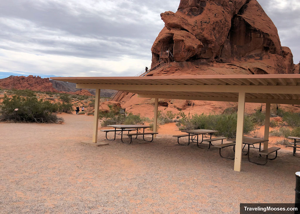 Picnic Tables covered by metal roof with Atlatl rock in background