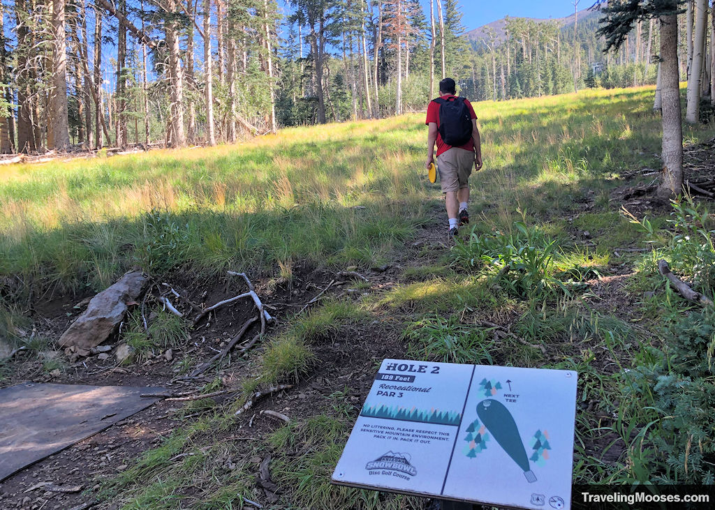 Man walking away from hole 2 at Snowbowl Disc Golf Course