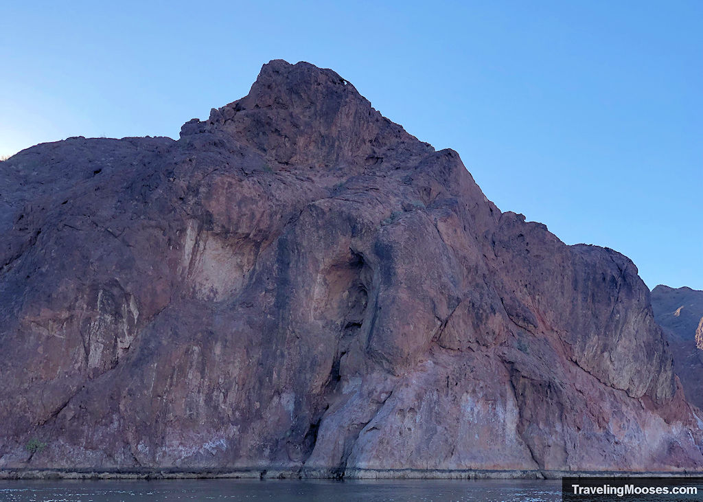 large rock formations with bathtub ring near the water line