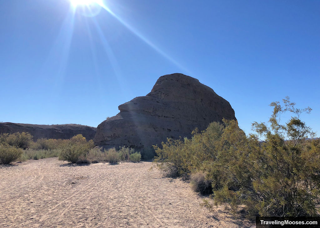 large rock known as castle rock resting atop a sandy beach