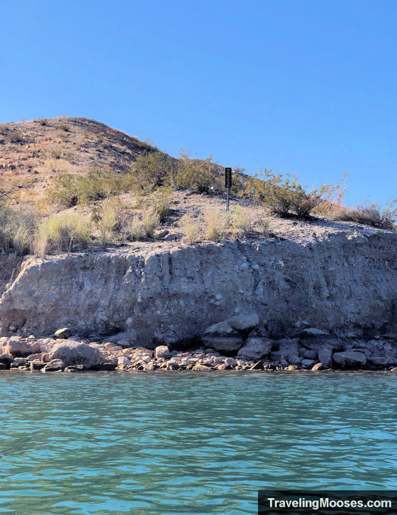 sign denoting mile marker 222 on a cliff seen from colorado river