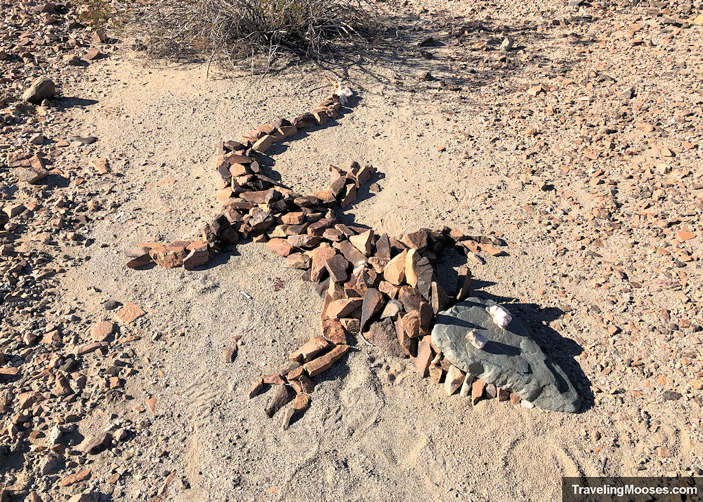 Stones on the desert floor arranged in the shape of a lizard with two quartz eyes