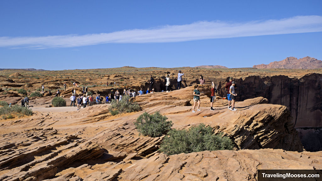 Many tourists scattered across a small lookout area with a 1,000 foot dropoff close to many.