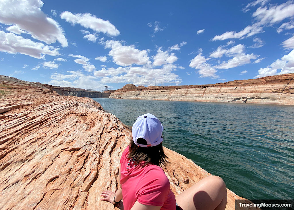 woman staring off in the distance towards the glen canyon dam at the end of green and blue colorado river waters