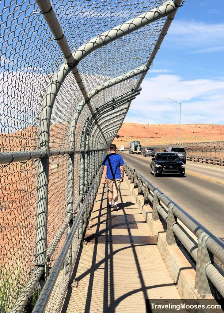 A man walking across the Glen Canyon Dam Bridge to see the views