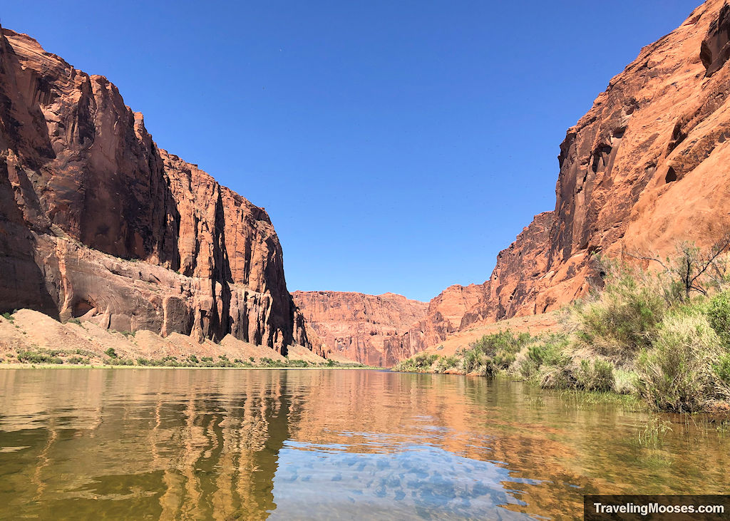 Crystal clear waters of Colorado River surrounded by the towering red color canyon walls of Glen Canyon