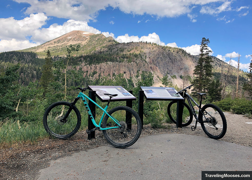 Bikes leaned up on a sign with mountains in the background along Lake Basin Trail in Mammoth