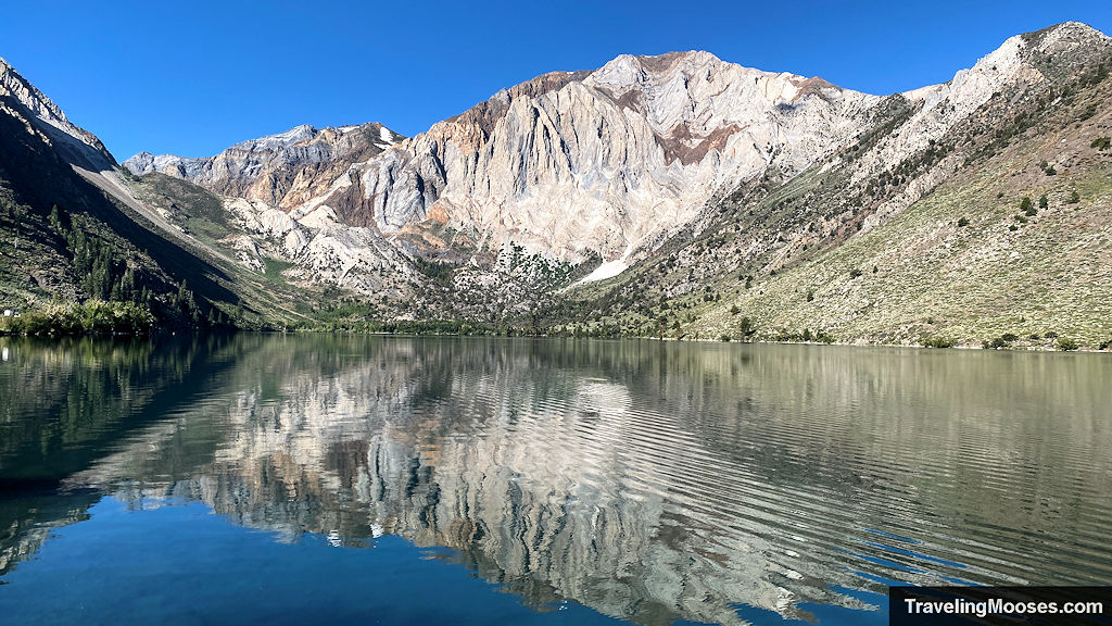 Sun shining on convict lake with the mountains reflection in the water