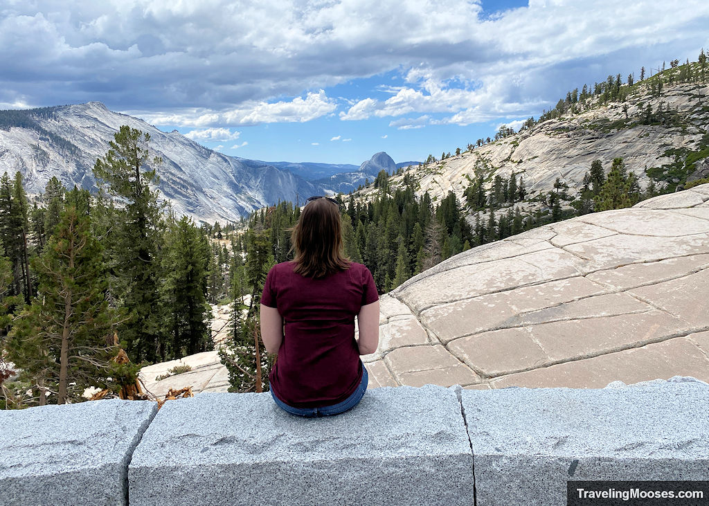 Women sitting on a stone wall enjoying views of the Yosemite Valley and Half Dome in the distance