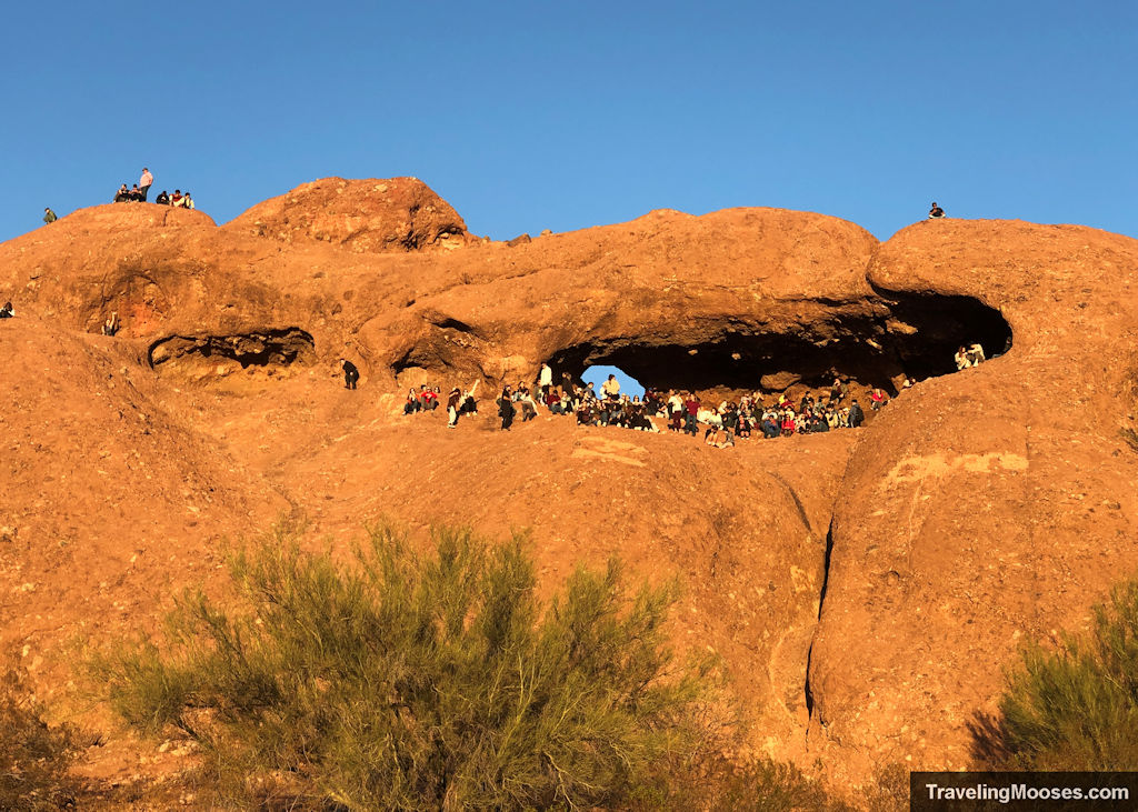 Multiple visitors sitting in a hollowed out rock area of Papago Park