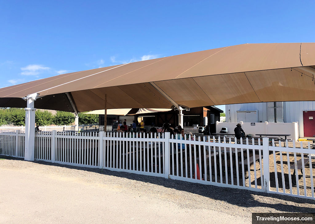Fenced off covered tent area with picnic tables and food for purchase