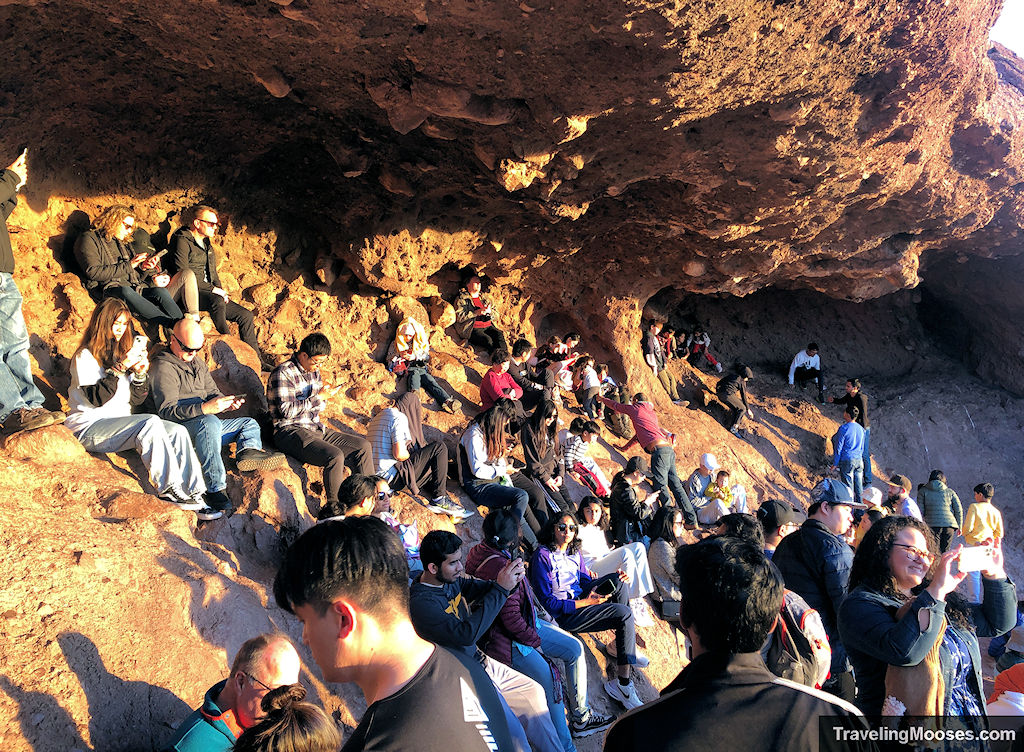 Crowds of people sitting on a rocky outcrop at the Hole in the Rock Trail in Papago Park