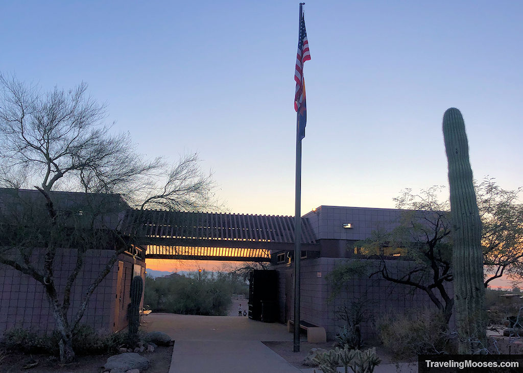 Stone building with a flag pole out front seen at dusk