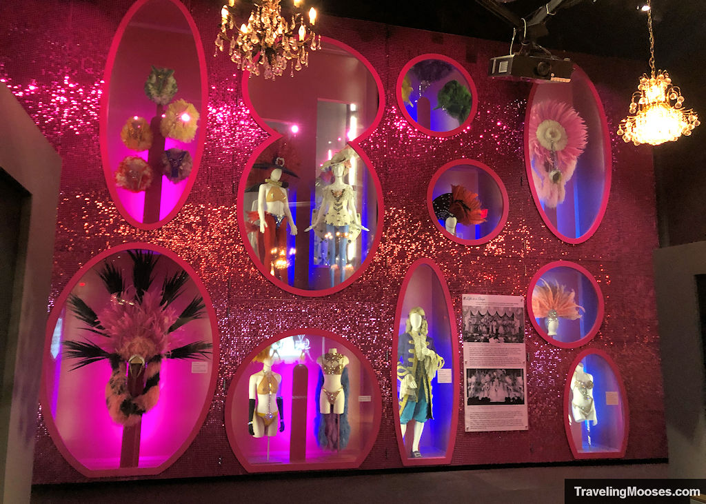 Pink sparkly wall with various cosumtes of showgirl costumes