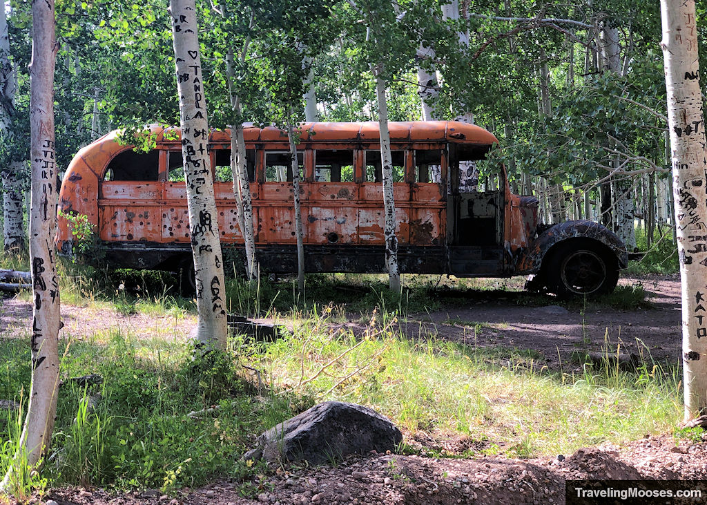 The Haunted Bus landmark on the Brian Head OHV loop, partially rusted and hidden in an aspen grove