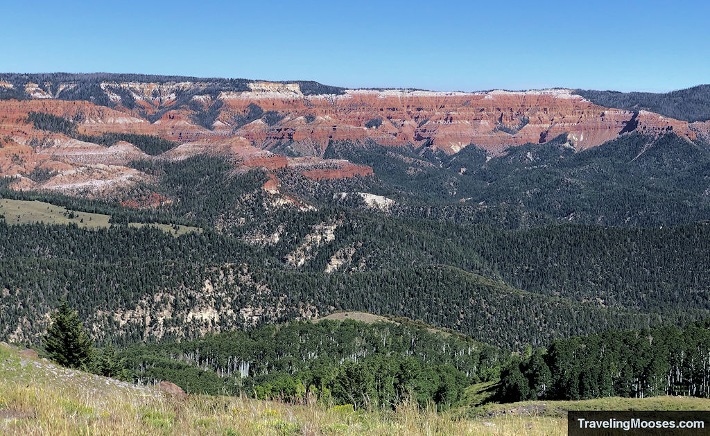 Expansive view of Cedar Breaks-style red rock cliffs and dense forest from High Mountain Overlook on the Brian Head OHV route.