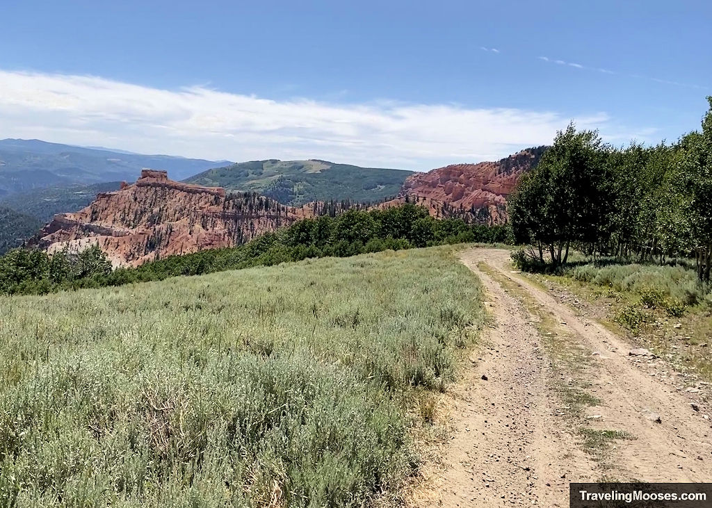Marathon Point viewpoint along the Brian Head OHV route, overlooking red rock cliffs, meadows, and forested peaks.