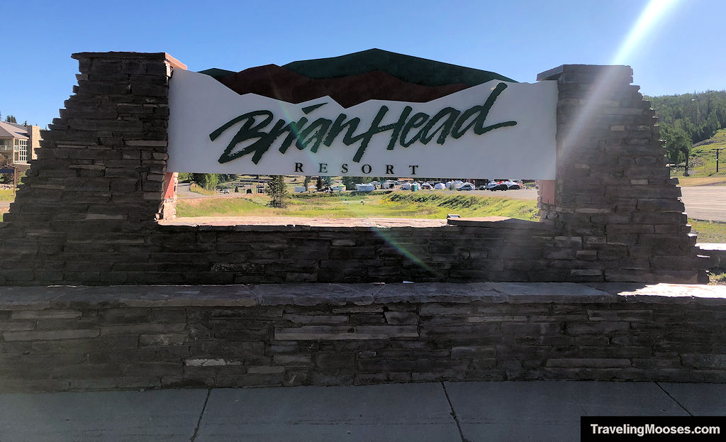 Brian Head Resort entrance sign with mountains and summer greenery in the background.