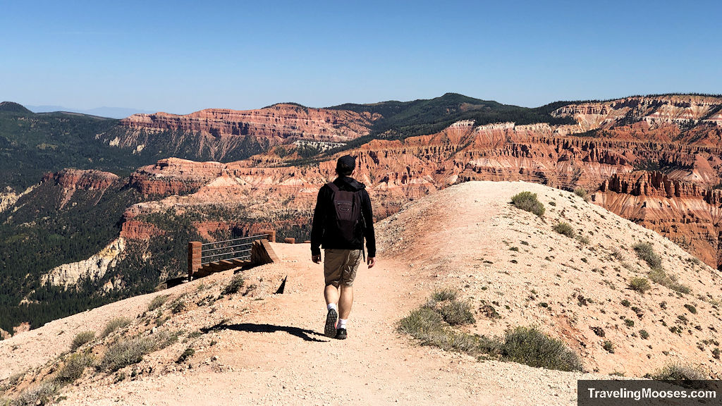 Man walking on a ridge towards red and white sandstone hills