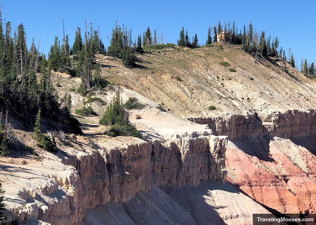 A cliff side with a faint trail and stairs winding close to the edge