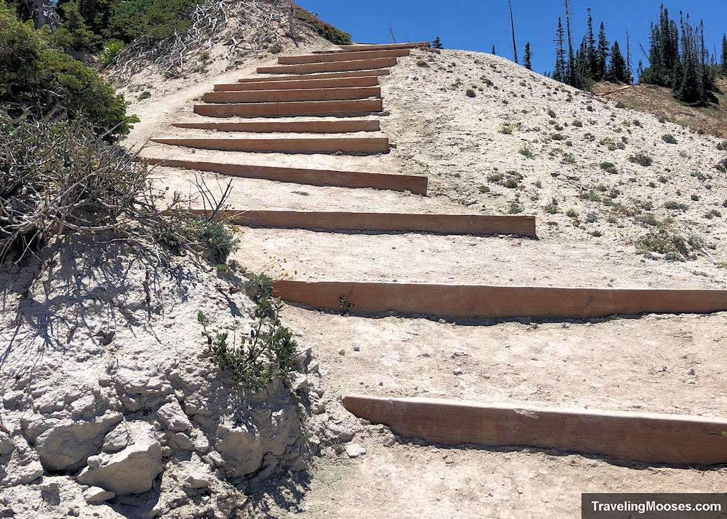 Trail curving up steep mountain side with wood slats for footing