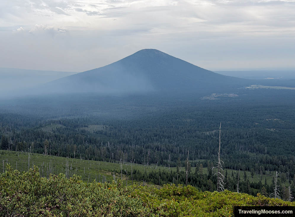 A dark cinder cone mountain shrouded in smoke