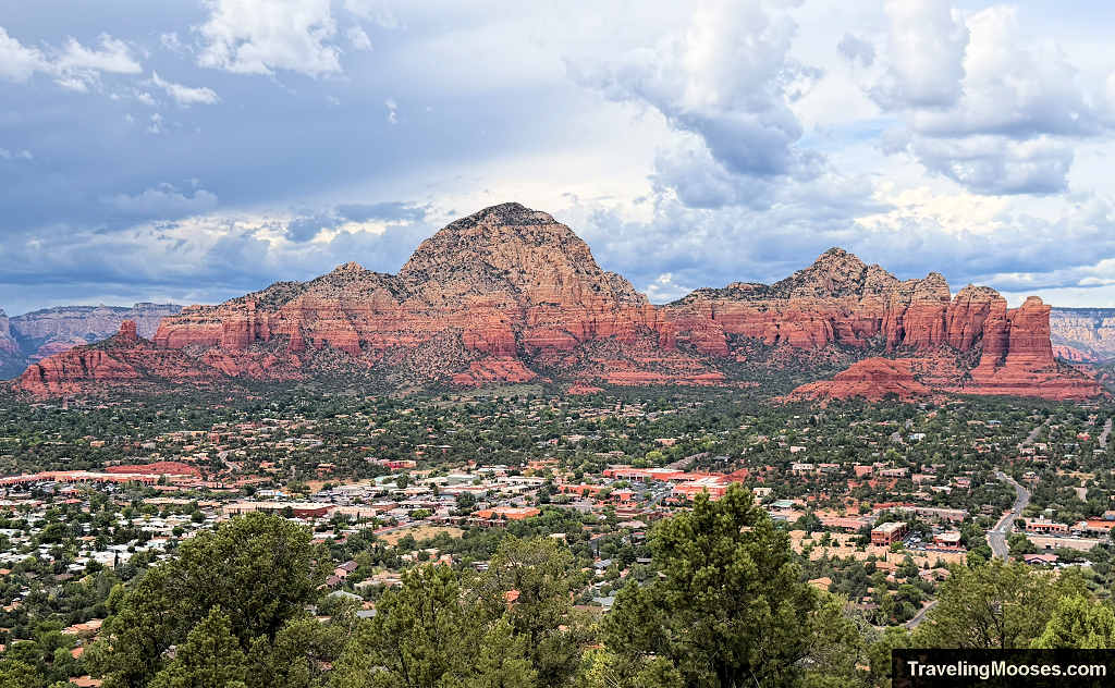 Panoramic elevated view of West Sedona neighborhoods and red sandstone formations including Thunder Mountain under cloudy skies.